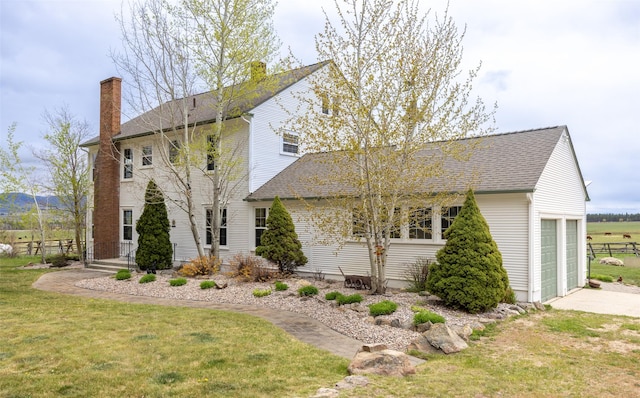 view of front of house with an attached garage, a chimney, roof with shingles, and a front lawn