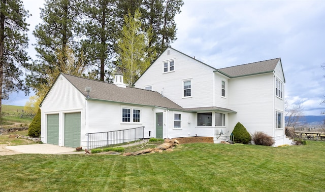 back of house with an attached garage, roof with shingles, a chimney, a lawn, and driveway
