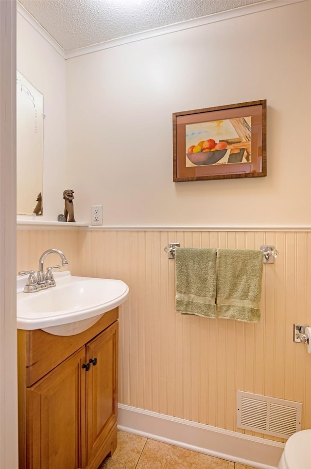 bathroom featuring visible vents, tile patterned flooring, wainscoting, vanity, and a textured ceiling