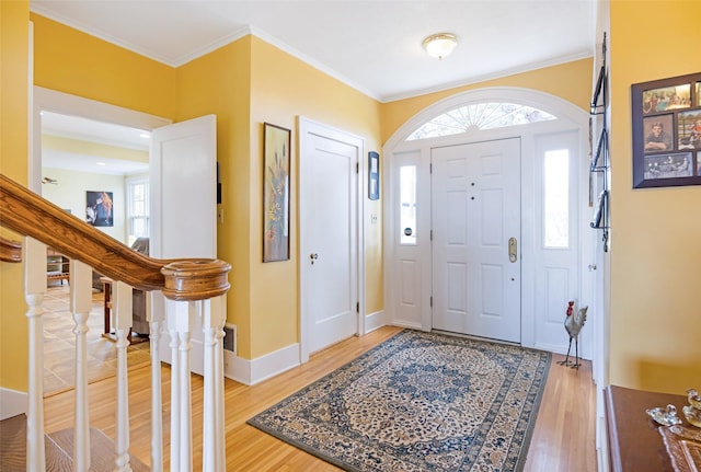 entryway with ornamental molding, a healthy amount of sunlight, and light wood-style floors