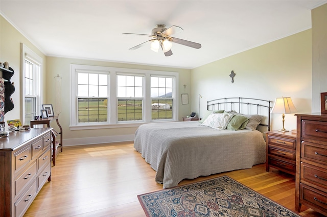 bedroom with light wood-style floors, ornamental molding, baseboards, and multiple windows