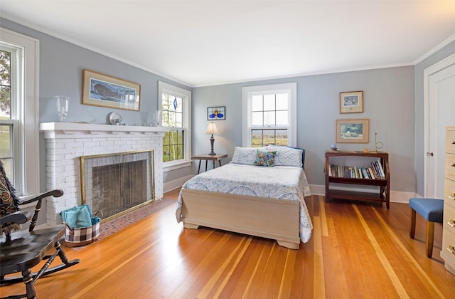 bedroom with crown molding, baseboards, a fireplace, and light wood-type flooring