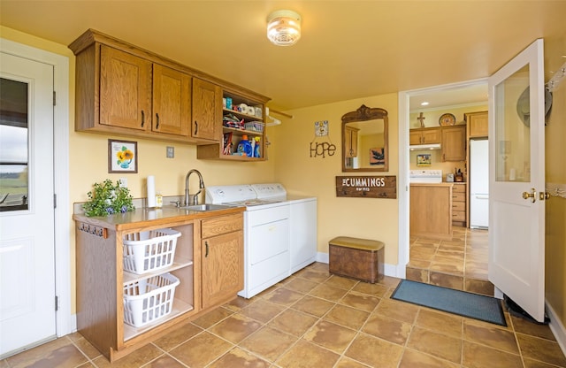 laundry room featuring baseboards, a sink, cabinet space, and washing machine and clothes dryer