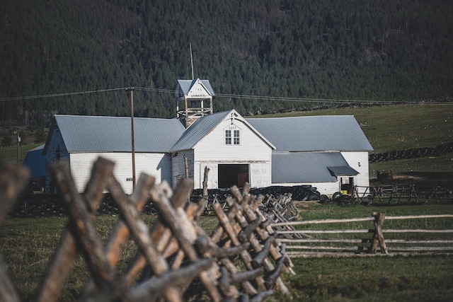 view of front facade featuring fence, a garage, a front yard, a view of trees, and metal roof
