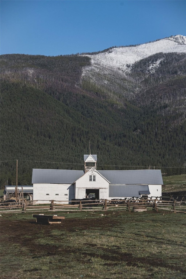 view of yard featuring a view of trees, a mountain view, an outbuilding, and fence