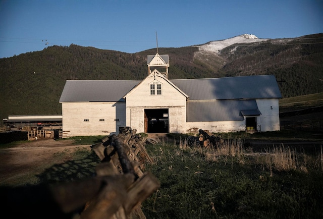 view of front of house with a barn, an outdoor structure, a mountain view, and brick siding