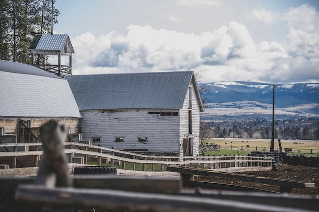 exterior details with fence, a mountain view, metal roof, and a barn