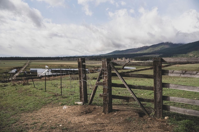 view of gate with a mountain view, fence, and a rural view