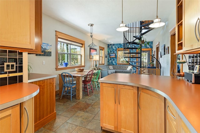kitchen with stone finish flooring, hanging light fixtures, light countertops, a peninsula, and open floor plan