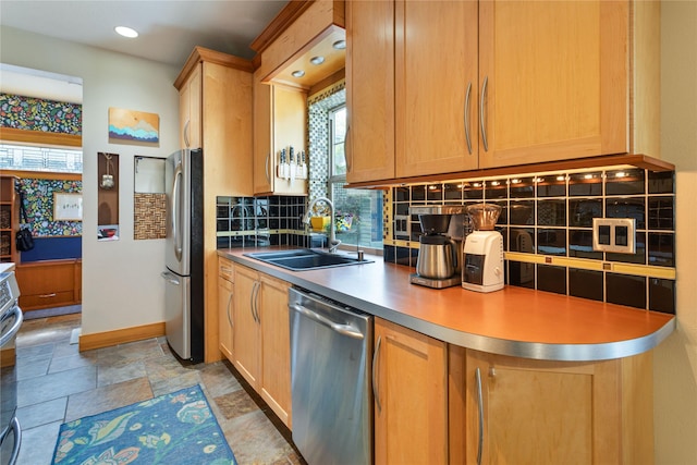 kitchen featuring a sink, stainless steel appliances, baseboards, stone finish flooring, and tasteful backsplash