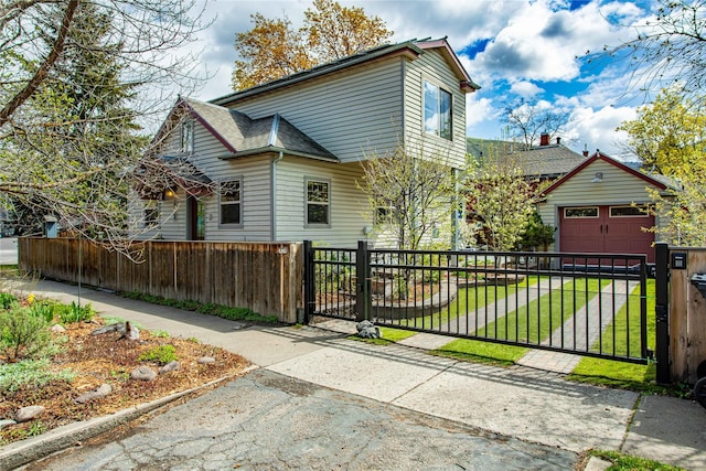 view of front of house with driveway, a fenced front yard, a front yard, a gate, and a garage