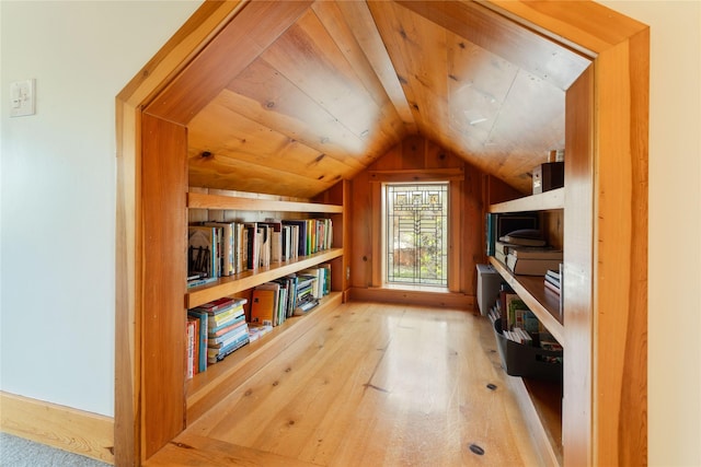interior space with wood-type flooring, wood walls, built in shelves, wooden ceiling, and vaulted ceiling