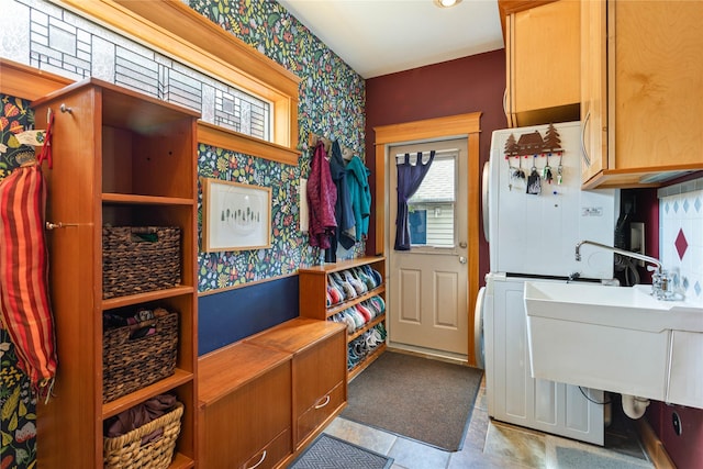 laundry room featuring washer / dryer, tile patterned flooring, wallpapered walls, and cabinet space