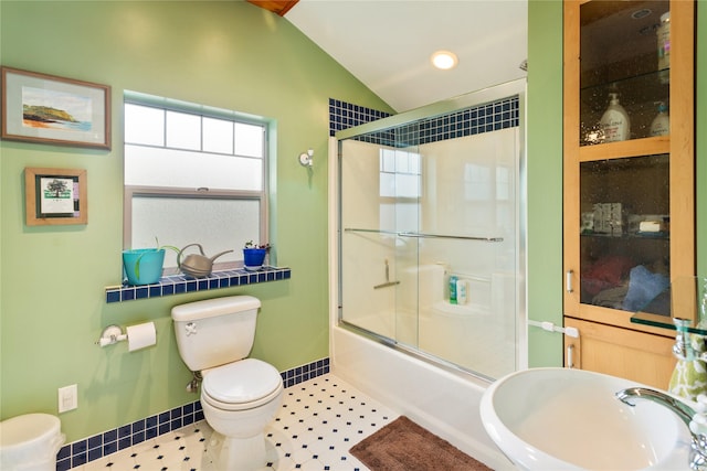 bathroom with lofted ceiling, shower / bath combination with glass door, toilet, baseboards, and a sink