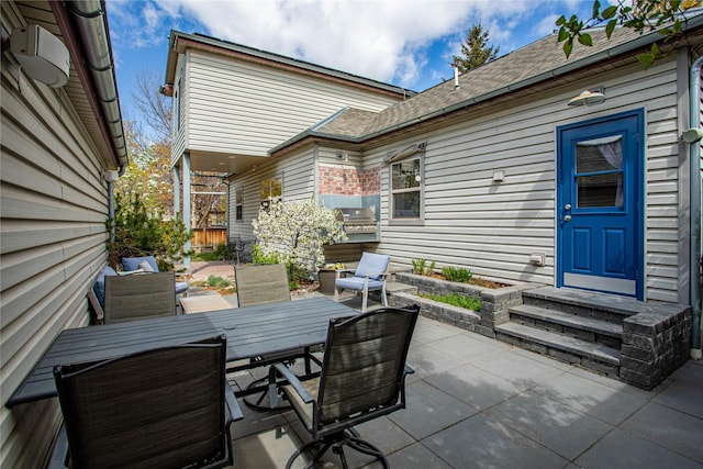 view of patio with outdoor dining space, entry steps, and a grill