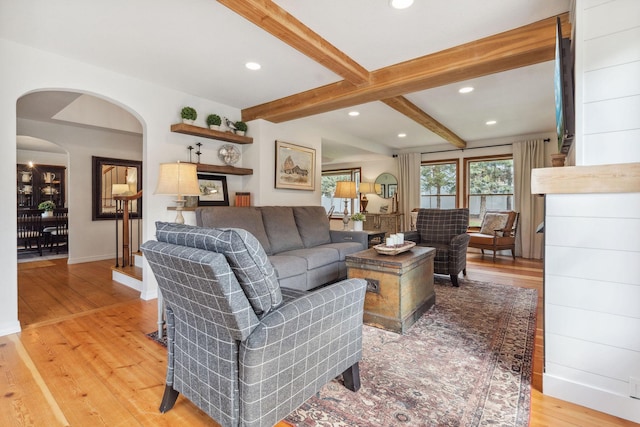 living area featuring arched walkways, baseboards, recessed lighting, and light wood finished floors