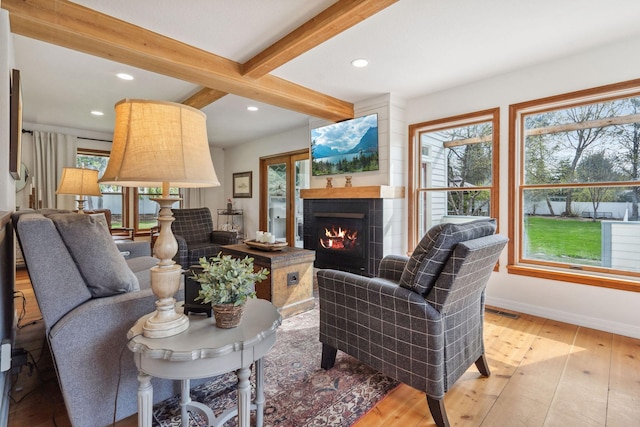 living room with hardwood / wood-style flooring, beam ceiling, baseboards, a warm lit fireplace, and recessed lighting
