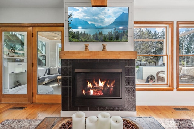 details with a fireplace, wood finished floors, and visible vents