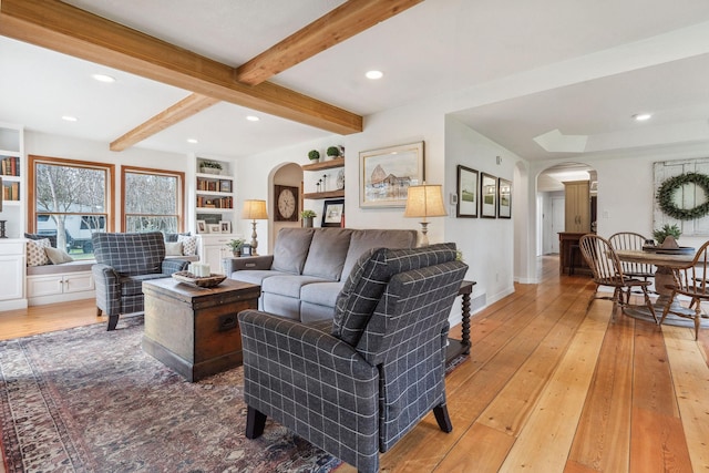 living area featuring recessed lighting, arched walkways, light wood finished floors, and beamed ceiling