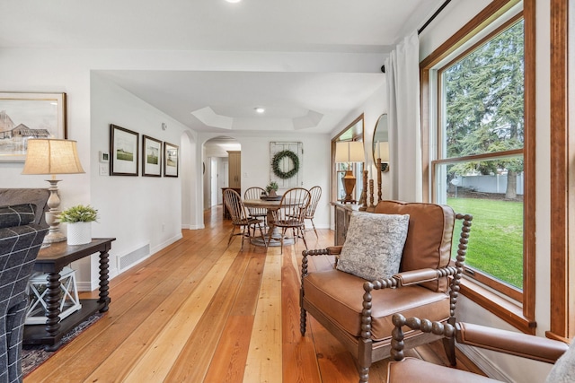living area with arched walkways, visible vents, plenty of natural light, and light wood finished floors