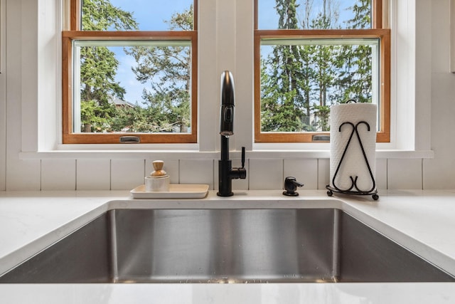 details featuring a sink, decorative backsplash, and light stone countertops