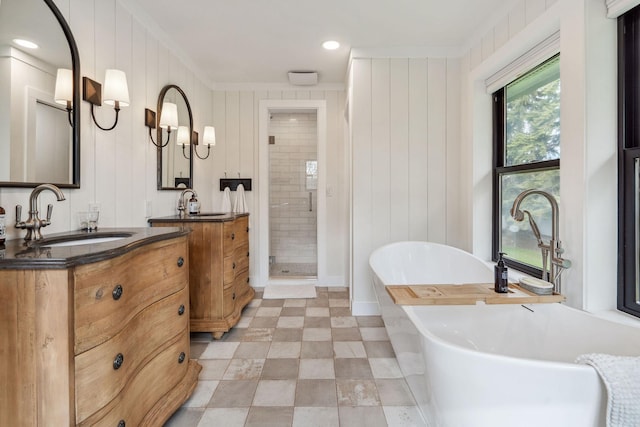 bathroom featuring a freestanding tub, a shower stall, two vanities, a sink, and ornamental molding