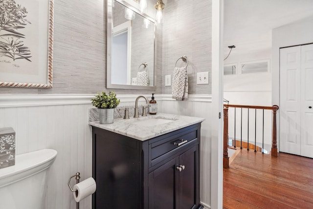 bathroom featuring vanity, wainscoting, wood finished floors, and toilet