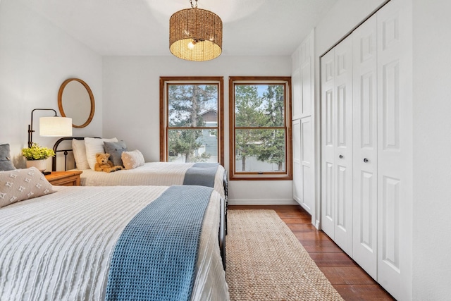 bedroom featuring a closet, baseboards, and dark wood-type flooring
