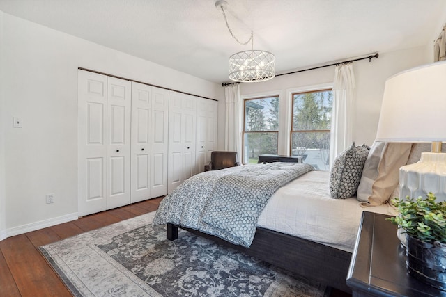bedroom featuring an inviting chandelier, baseboards, a closet, and hardwood / wood-style flooring