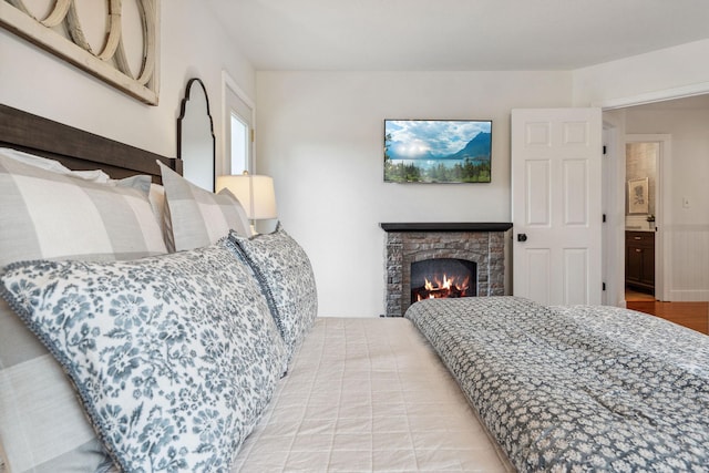 bedroom with wood finished floors and a fireplace