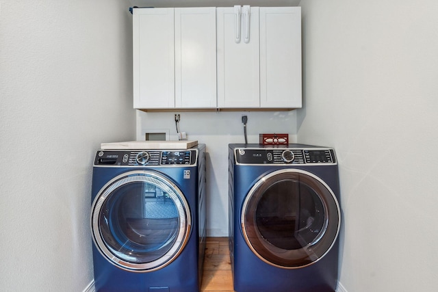 laundry area featuring cabinet space, baseboards, wood finished floors, and washing machine and clothes dryer