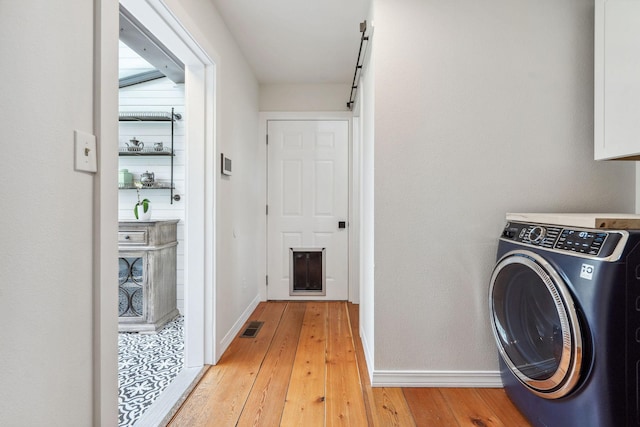 laundry area featuring cabinet space, light wood finished floors, baseboards, washer / dryer, and visible vents