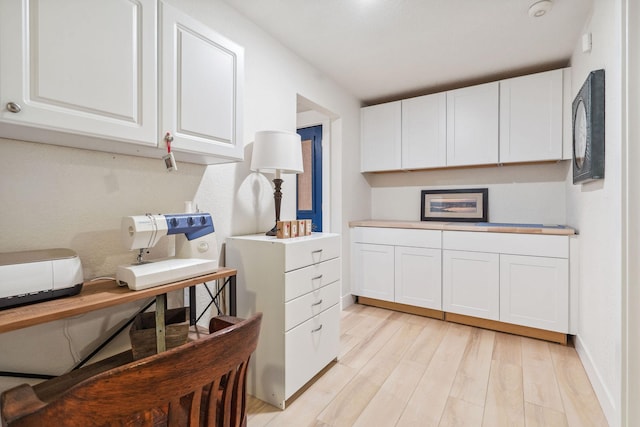 kitchen featuring light countertops, baseboards, white cabinets, and light wood finished floors