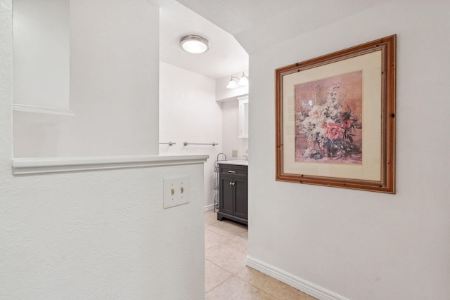 corridor featuring baseboards and light tile patterned floors