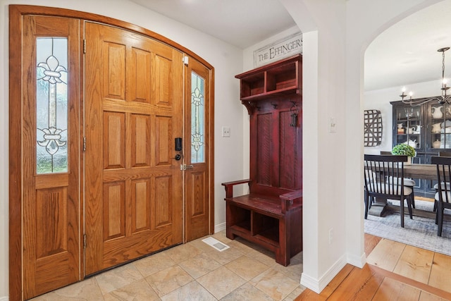 mudroom with visible vents, arched walkways, baseboards, and an inviting chandelier