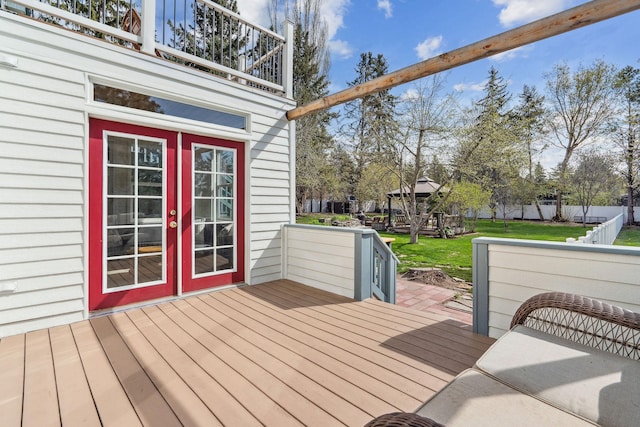 wooden deck with a lawn and french doors