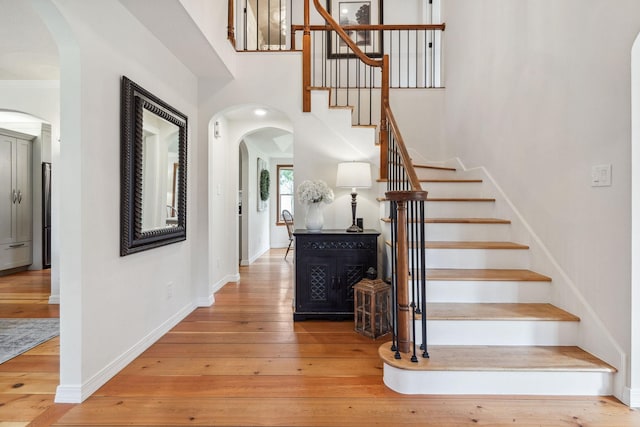 stairway with baseboards, wood-type flooring, and arched walkways