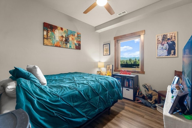 bedroom with a ceiling fan, wood finished floors, and visible vents