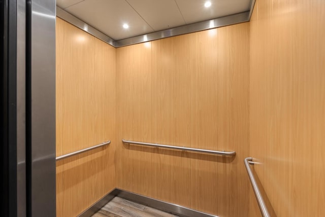 interior details with recessed lighting, elevator, and wood finished floors