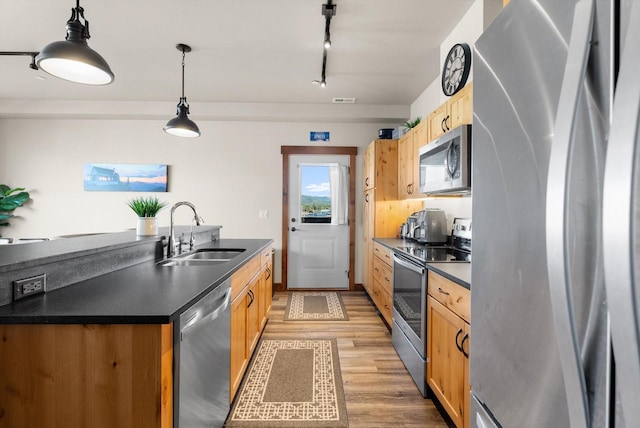 519 Nucleus Ave Unit 303, Columbia Falls, MT 59912 - kitchen with stainless steel appliances, dark countertops, light wood-style flooring, pendant lighting, and track lighting