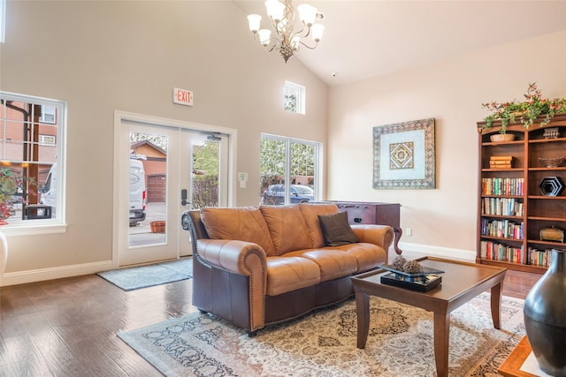living room featuring an inviting chandelier, baseboards, high vaulted ceiling, and wood finished floors