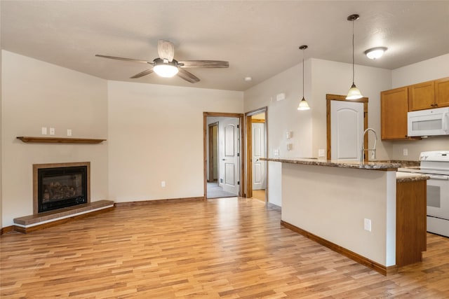 kitchen featuring light wood-style floors, baseboards, ceiling fan, and white appliances