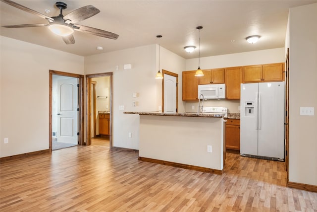 kitchen with ceiling fan, brown cabinetry, a peninsula, light wood finished floors, and white appliances