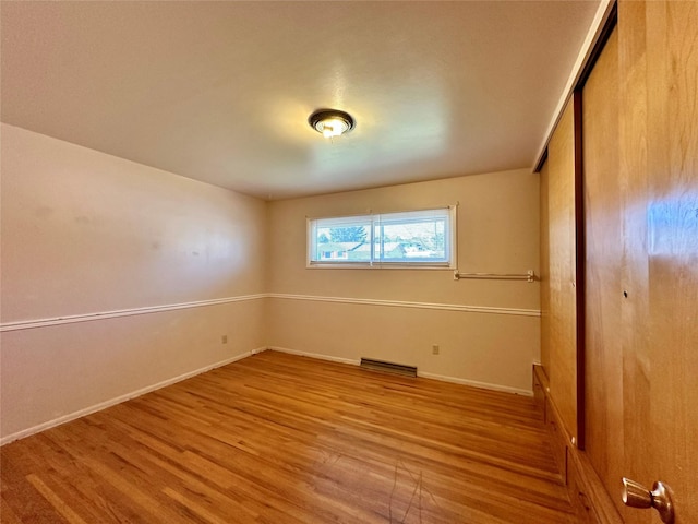 unfurnished bedroom with a closet, baseboards, wood finished floors, and visible vents