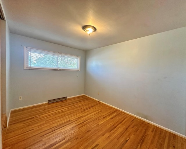 empty room with light wood-style floors, baseboards, and visible vents