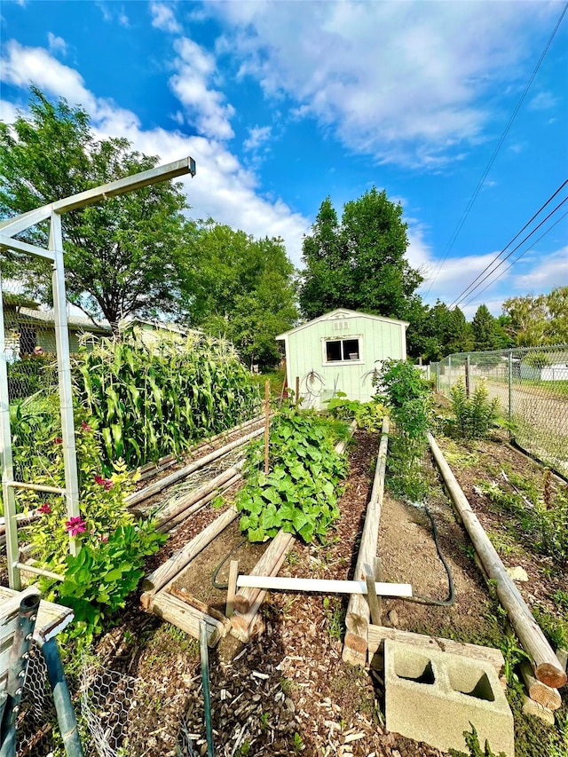 view of yard featuring fence, a storage unit, an outbuilding, and a vegetable garden