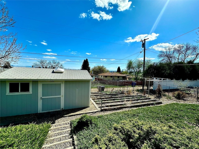 view of yard featuring fence, an outdoor structure, and a storage unit