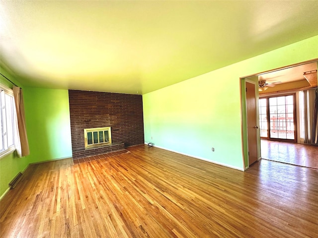 unfurnished living room featuring baseboards, ceiling fan, a fireplace, and wood finished floors