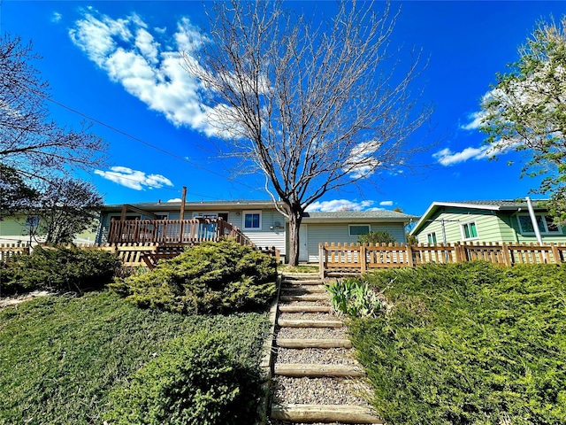 rear view of house featuring fence and a wooden deck