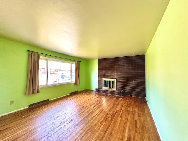unfurnished living room featuring baseboards, wood finished floors, and a fireplace